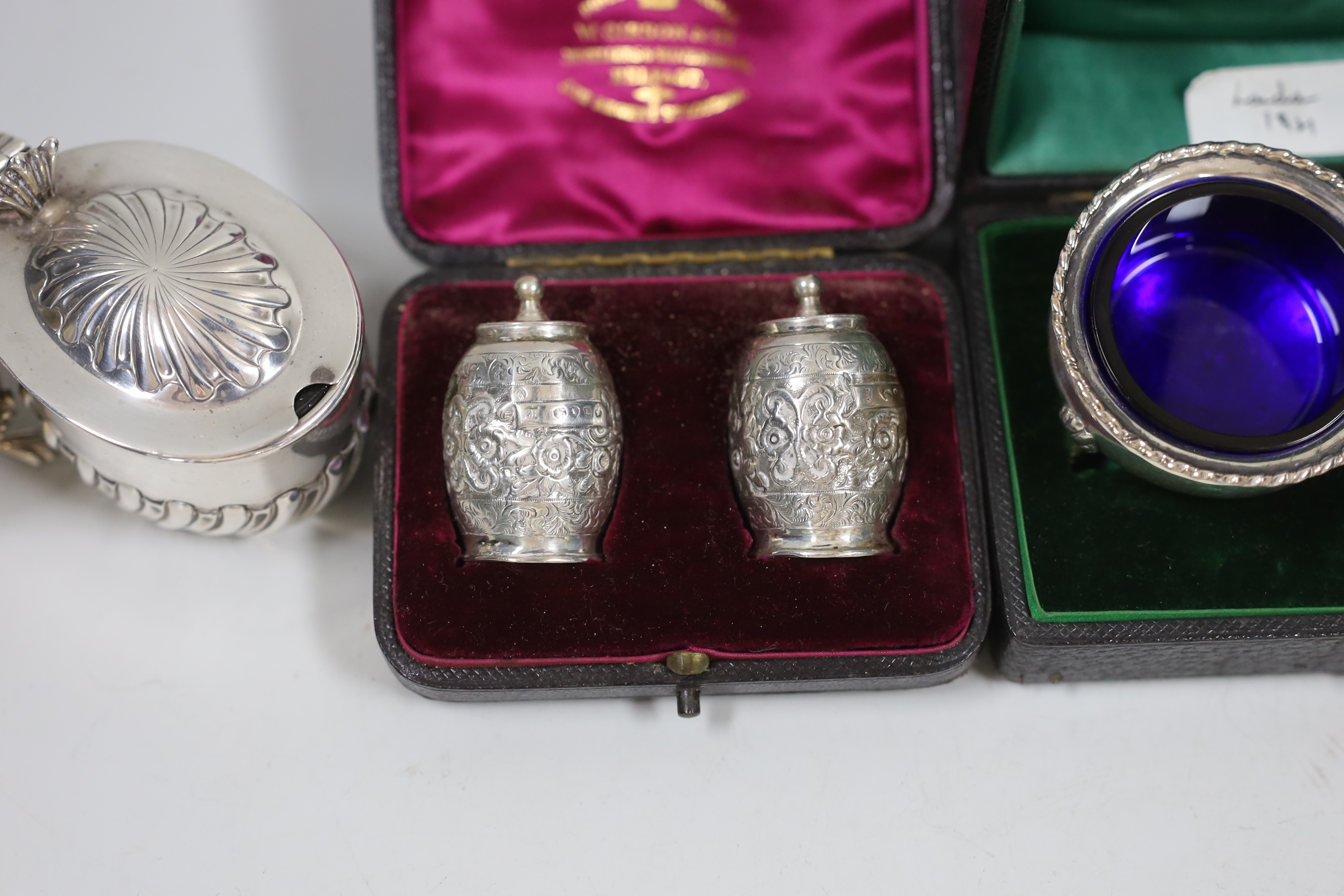 Two cased pairs of silver condiments including chased pepperettes, 45mm and four other silver condiments.